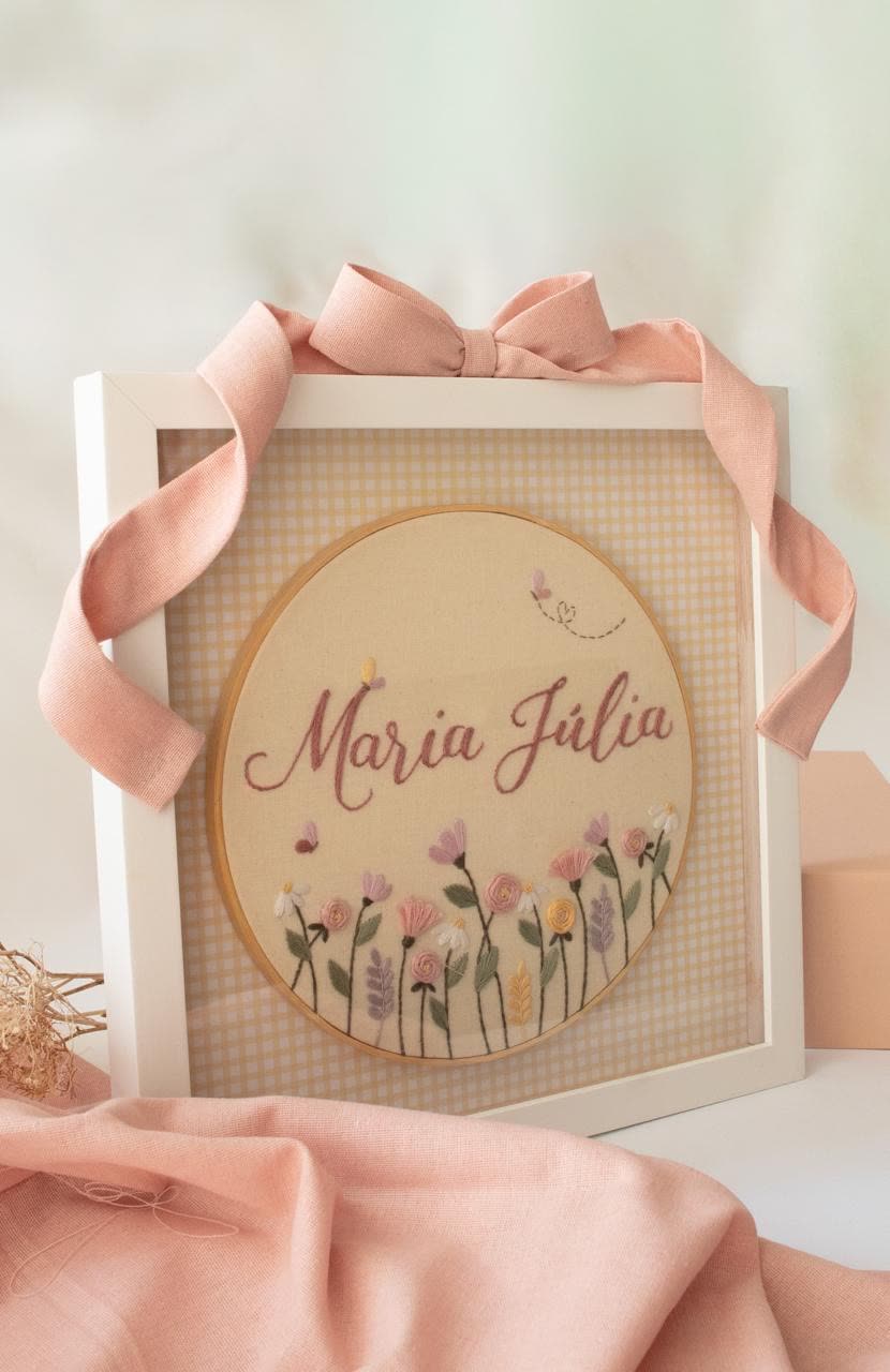 Porta-maternidade com o nome Maria Júlia e flores do campo bordadas, em moldura com laço rosa