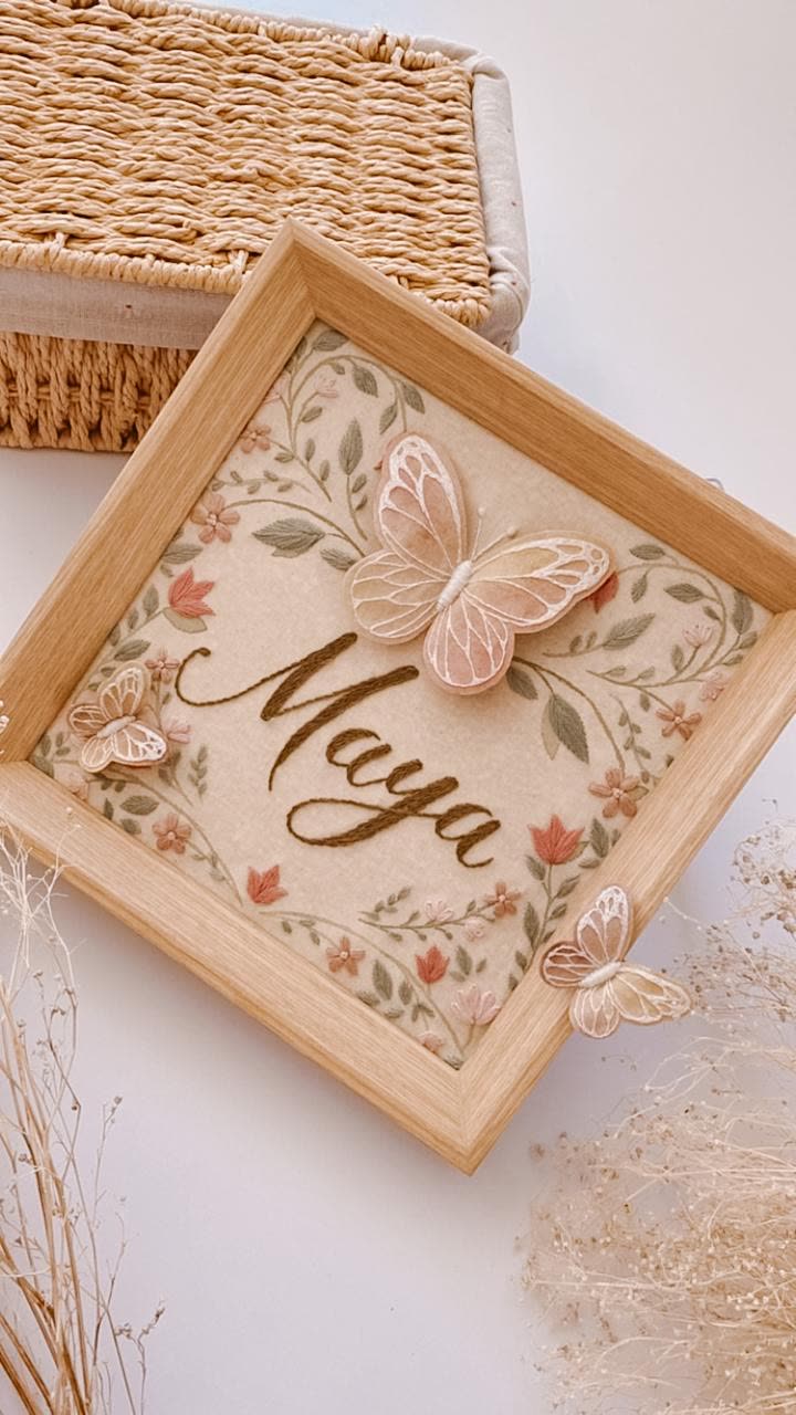 Porta-maternidade com o nome Maya, guirlanda de flores e borboletas, em moldura de madeira