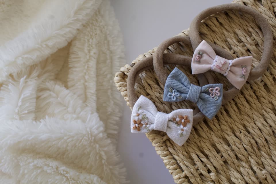 Faixas de recém-nascida com laços bordados em rosa, azul e branco