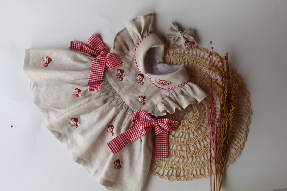 Vestido de linho cru com bordados vermelhos e laços xadrez